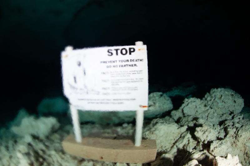 Underwater cenote warning sign on the cave floor: STOP. Prevent Your Death.