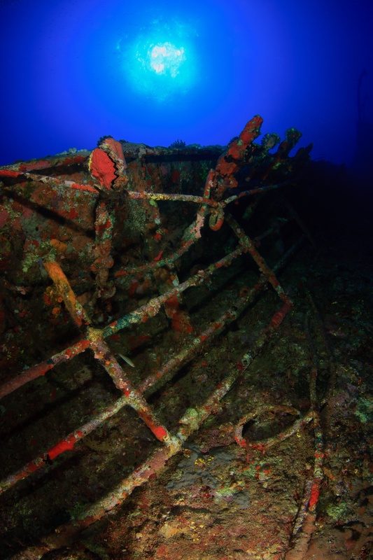 Coral-coated railings of the Aida climb toward a bright sunball in clear Red Sea blue.